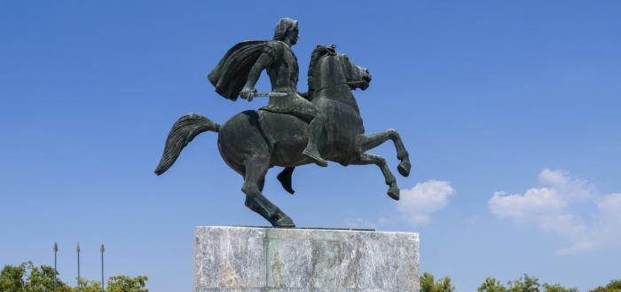 In the blue sky rises the statue of Alexander the Great on horseback, drawing his swor.